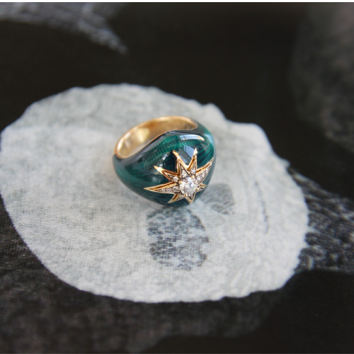 Gold and green ring with star design on a textured surface