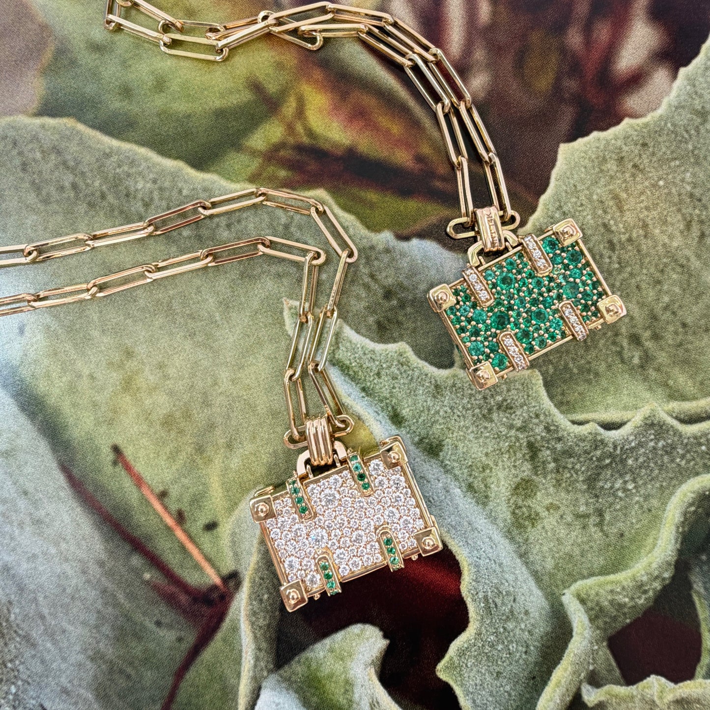 Gold necklaces with green gemstone pendants on a textured surface