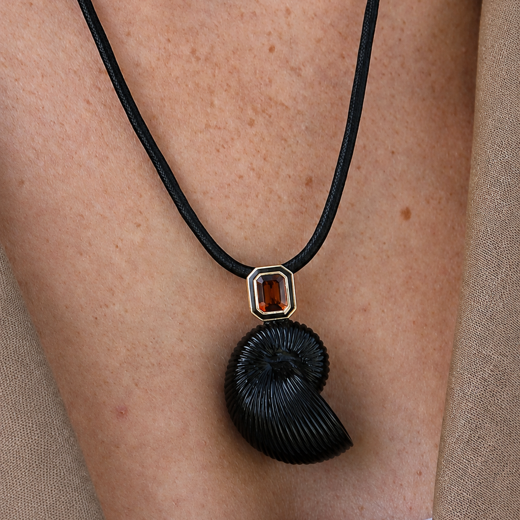 Necklace with a black pendant and red gemstone on a person's neck