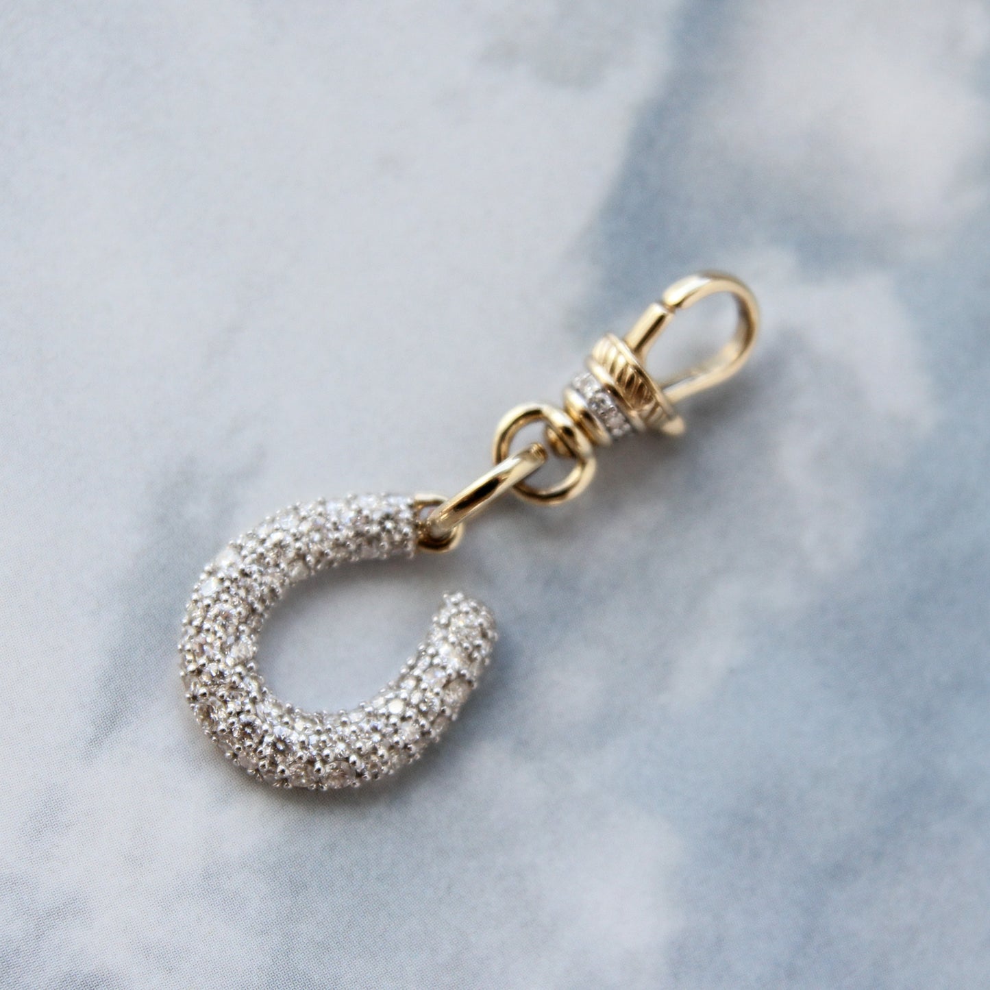 Silver keychain with gold clasp on a light blue marble background