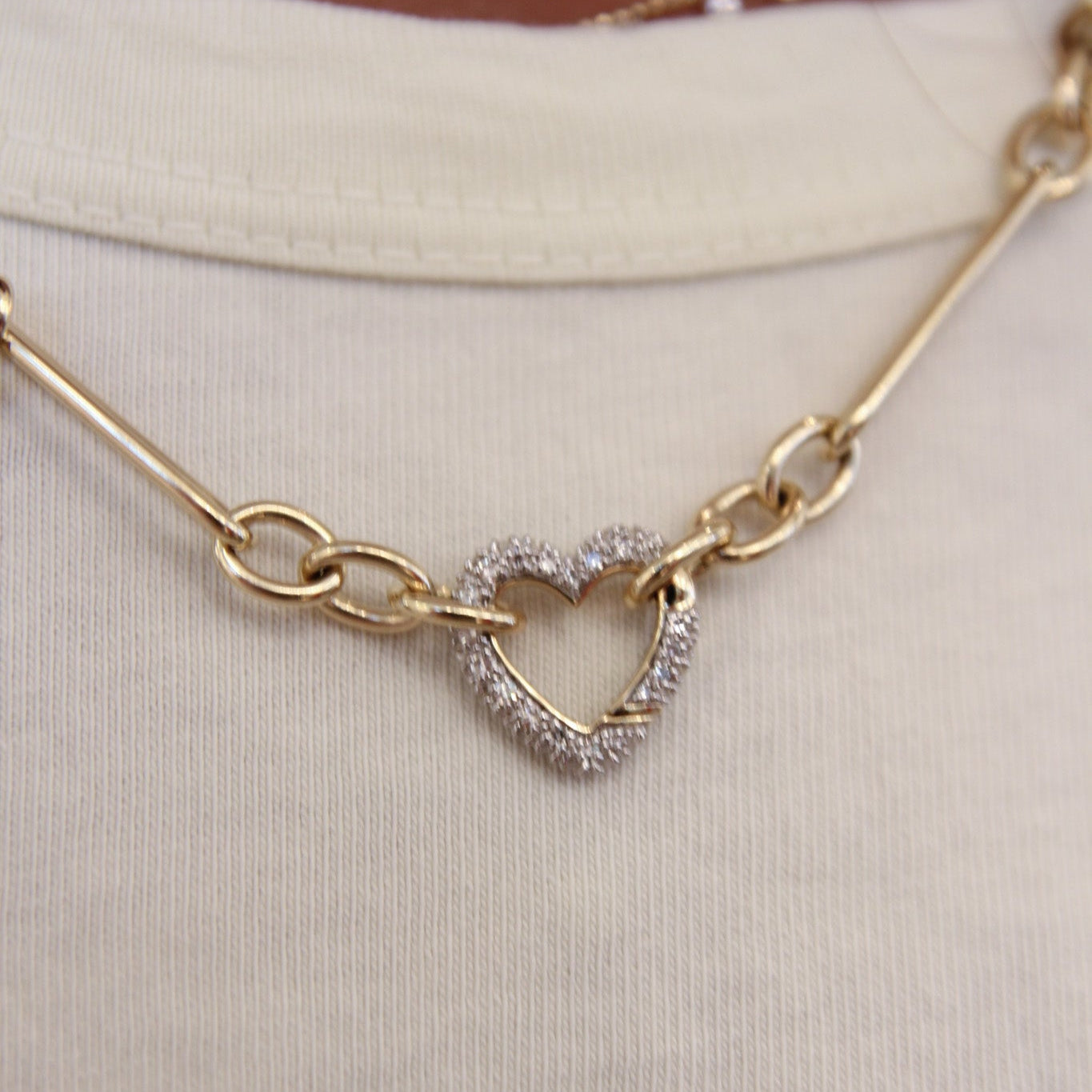 Gold necklace with heart-shaped pendant on a plain background