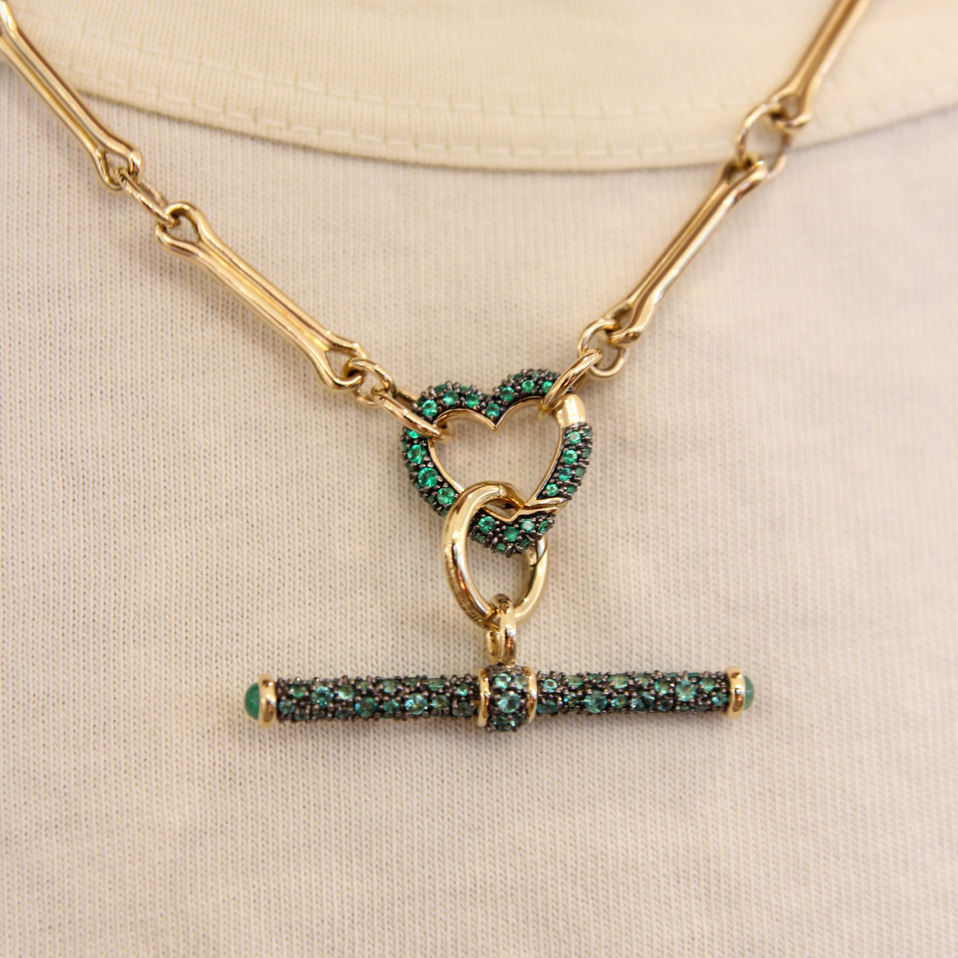 Gold necklace with green gemstone pendants on a beige background