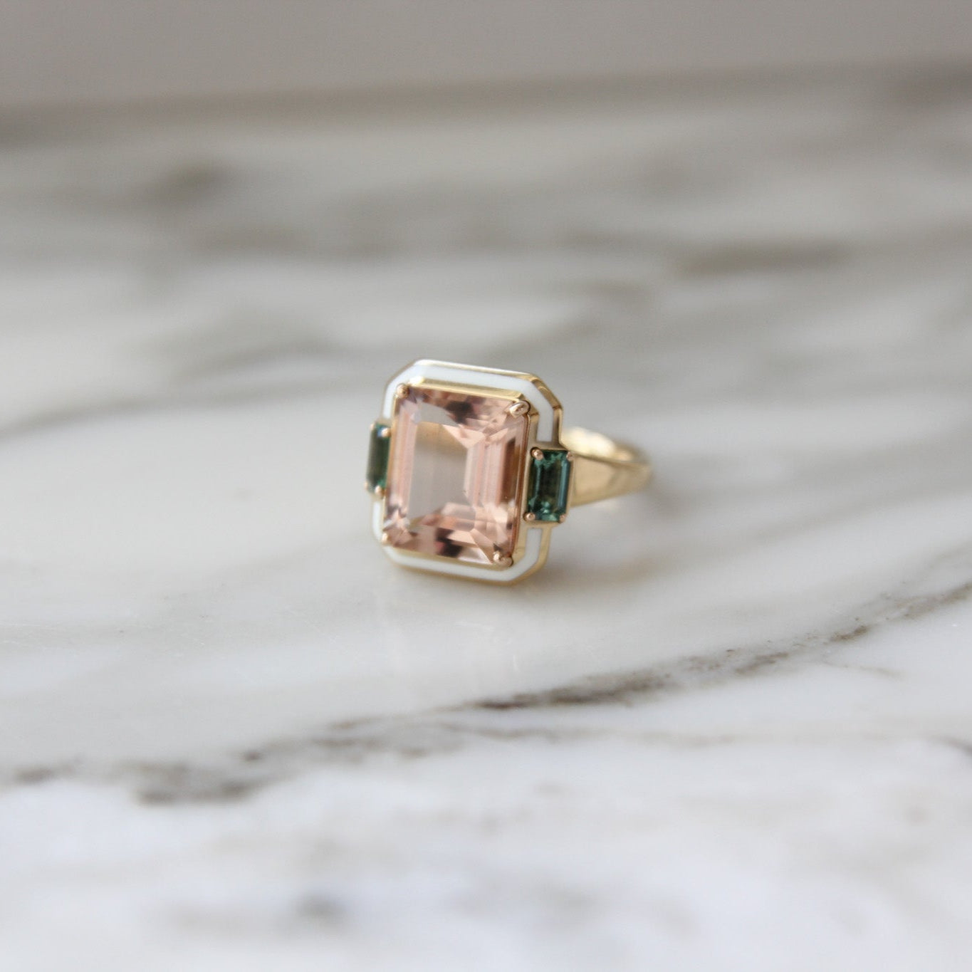 Gold ring with a green gemstone on a marble surface