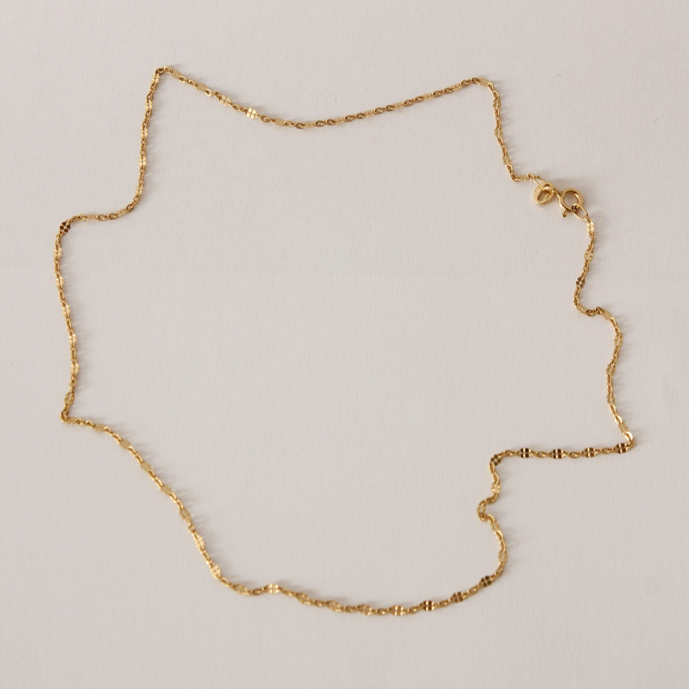 Gold chain necklace on a light gray background