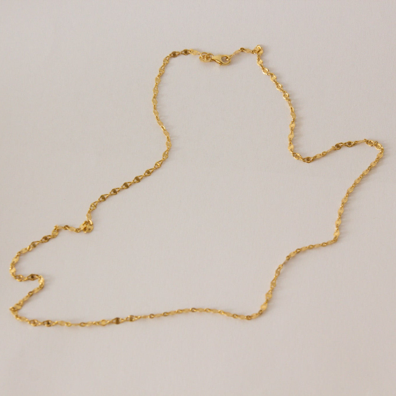 Gold chain necklace on a light beige background