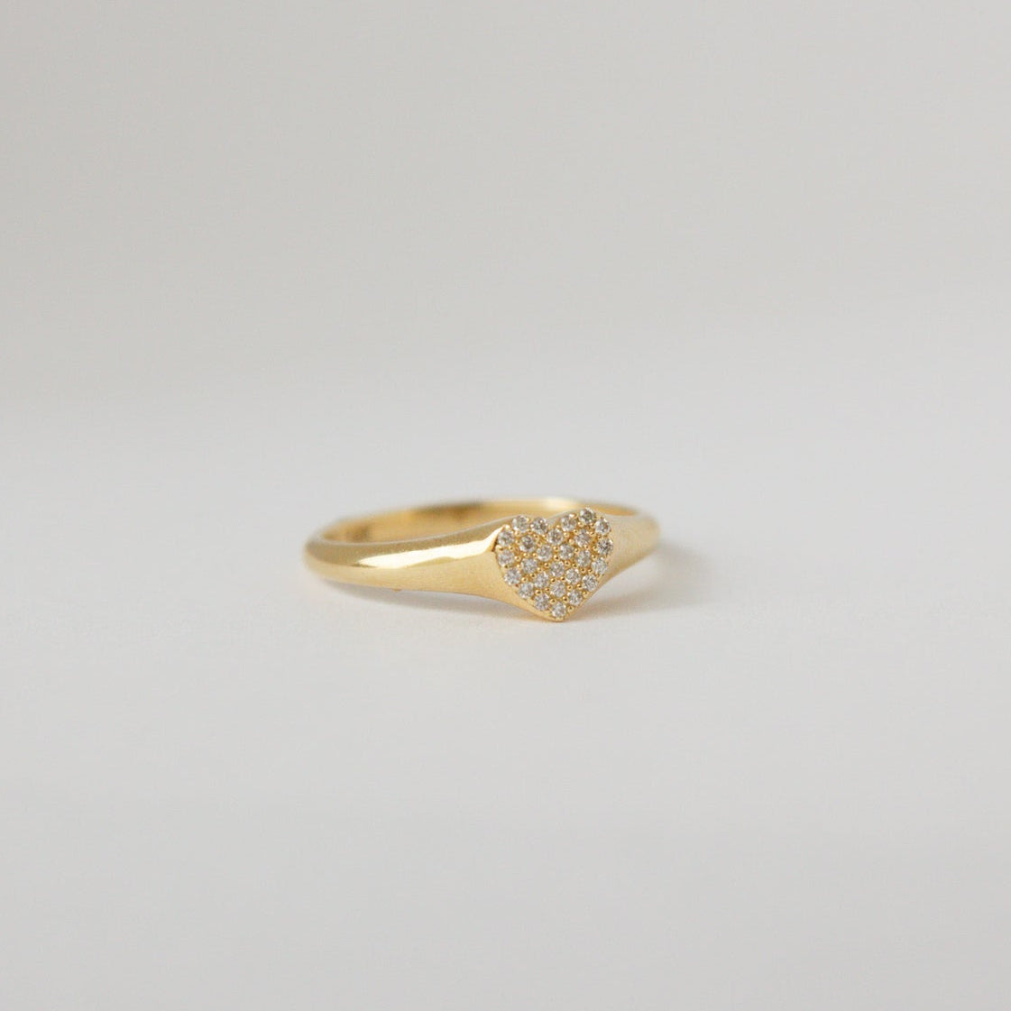 Gold ring with small diamonds on a light gray background