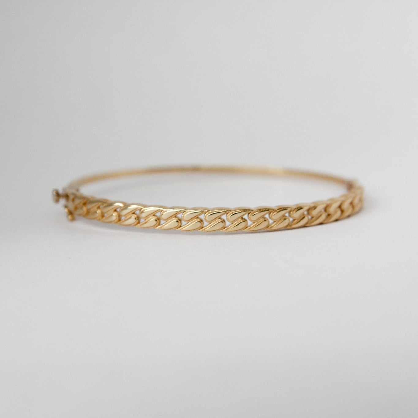 Gold bracelet on a light gray background