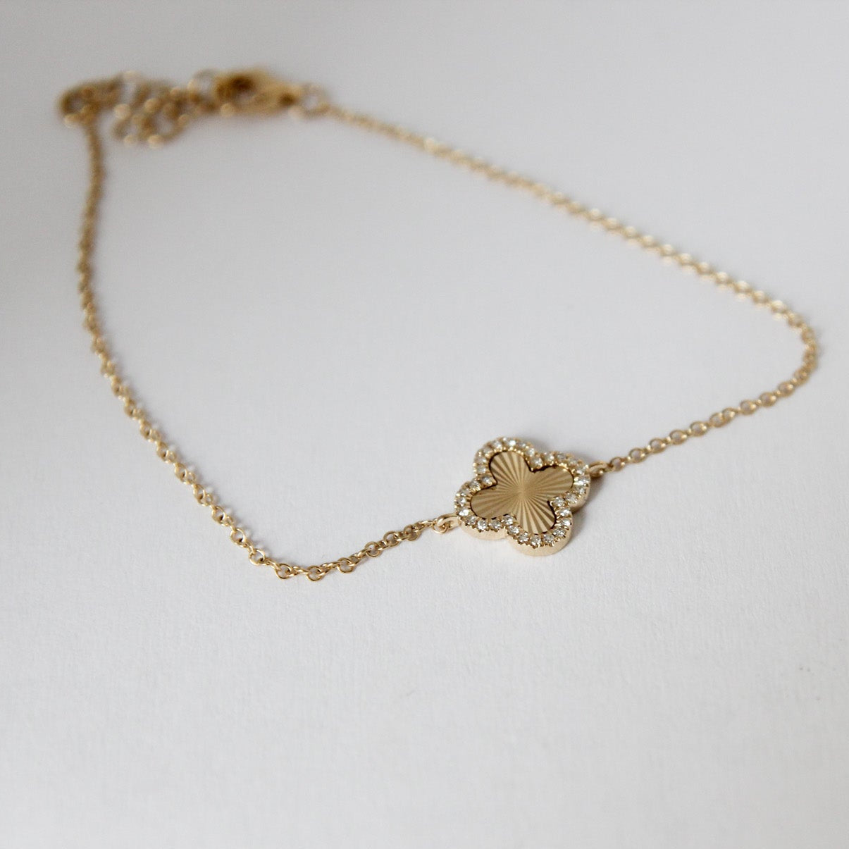 Gold bracelet with a heart-shaped clasp on a light gray background