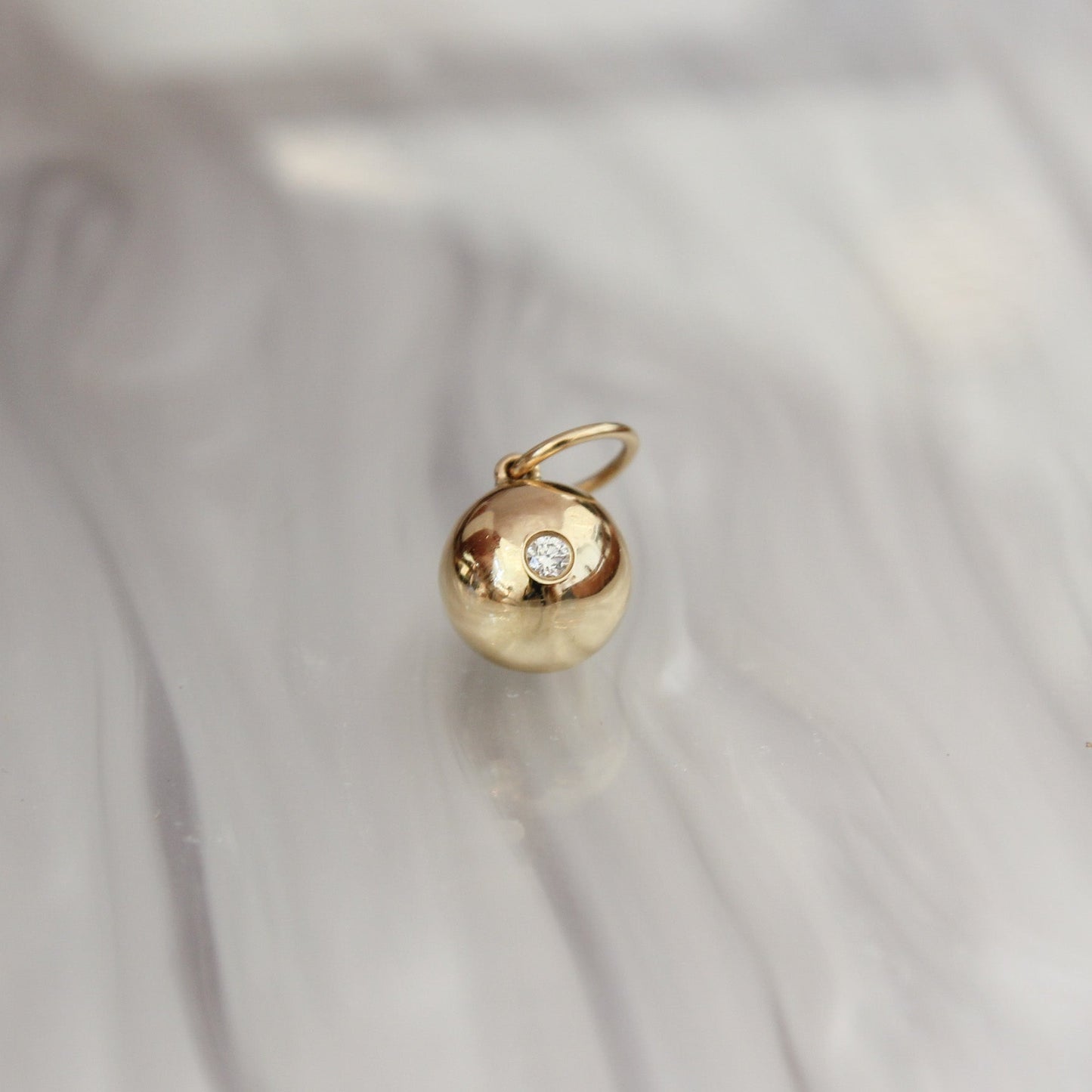 Gold pendant with a diamond on a light fabric background