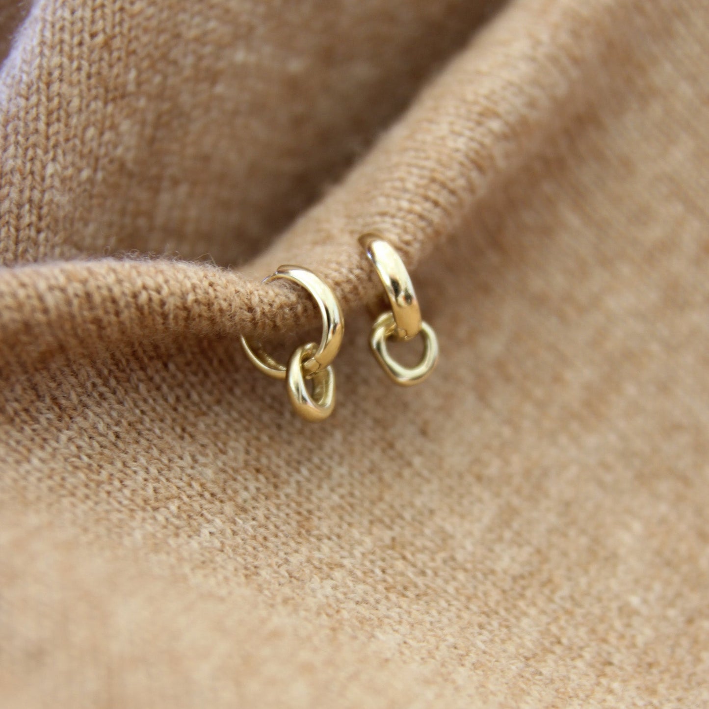 Gold hoop earrings on a beige fabric background
