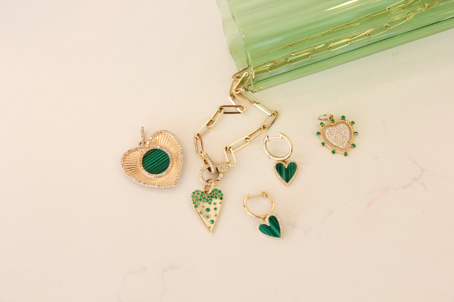 Gold and green heart-shaped charms on a beige background