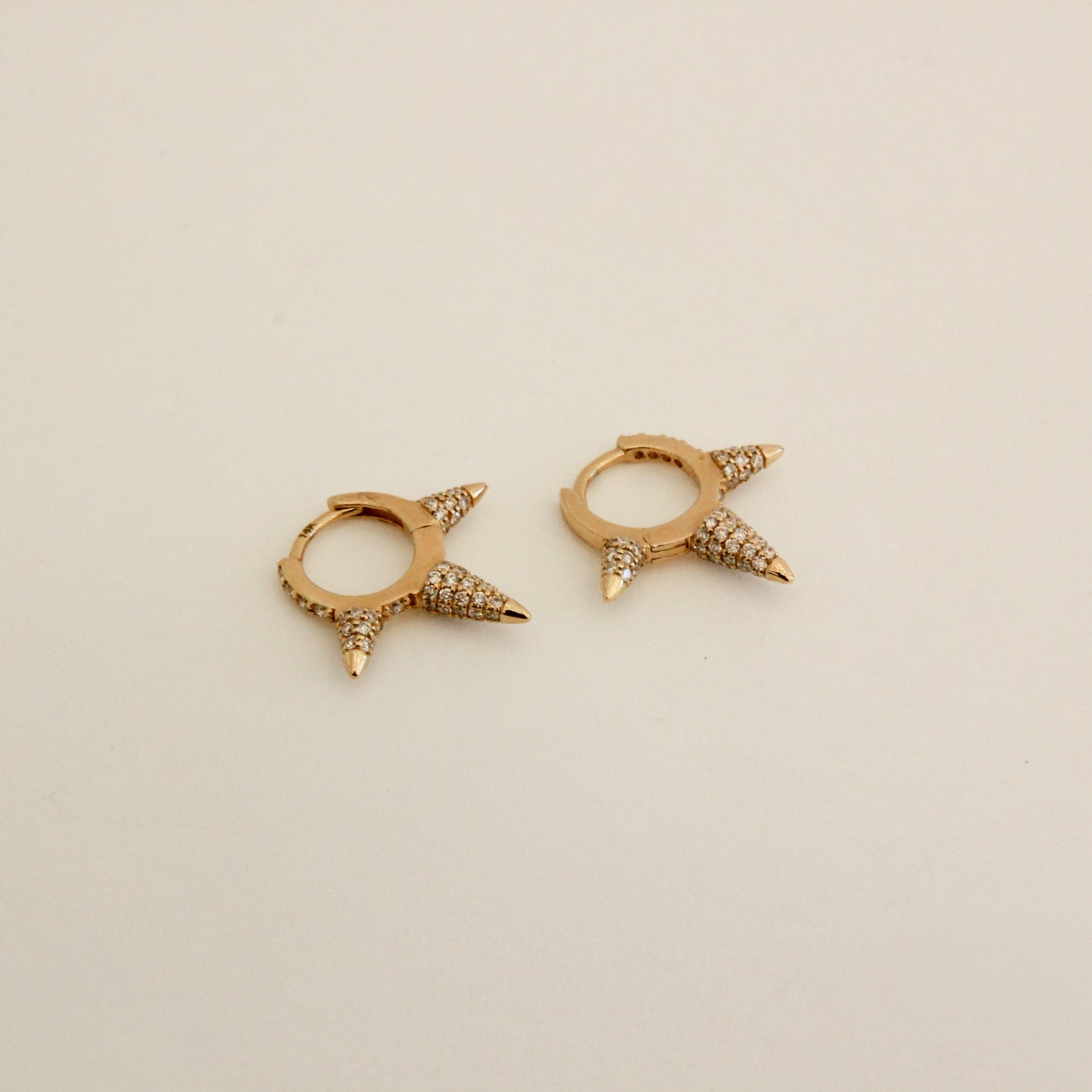 Gold hoop earrings with spike designs on a beige background