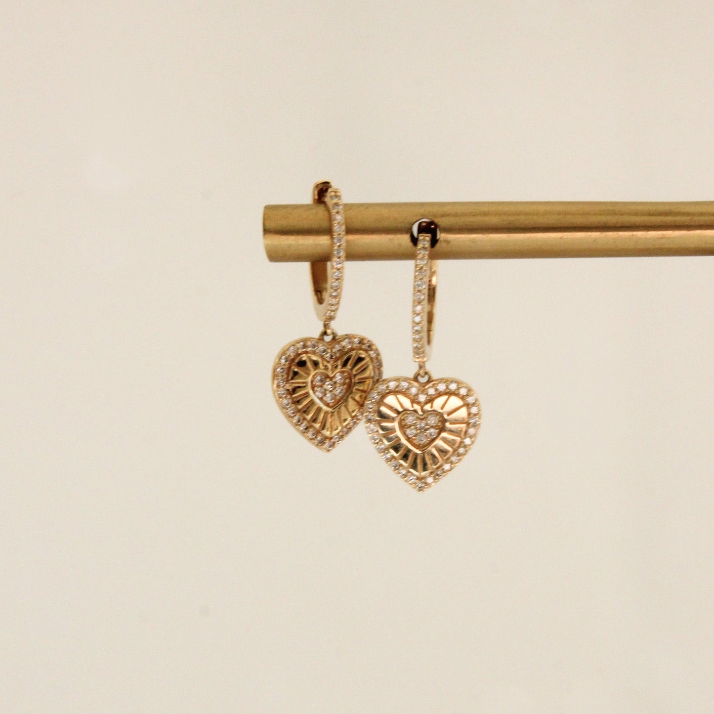 Heart-shaped gold earrings on a beige background