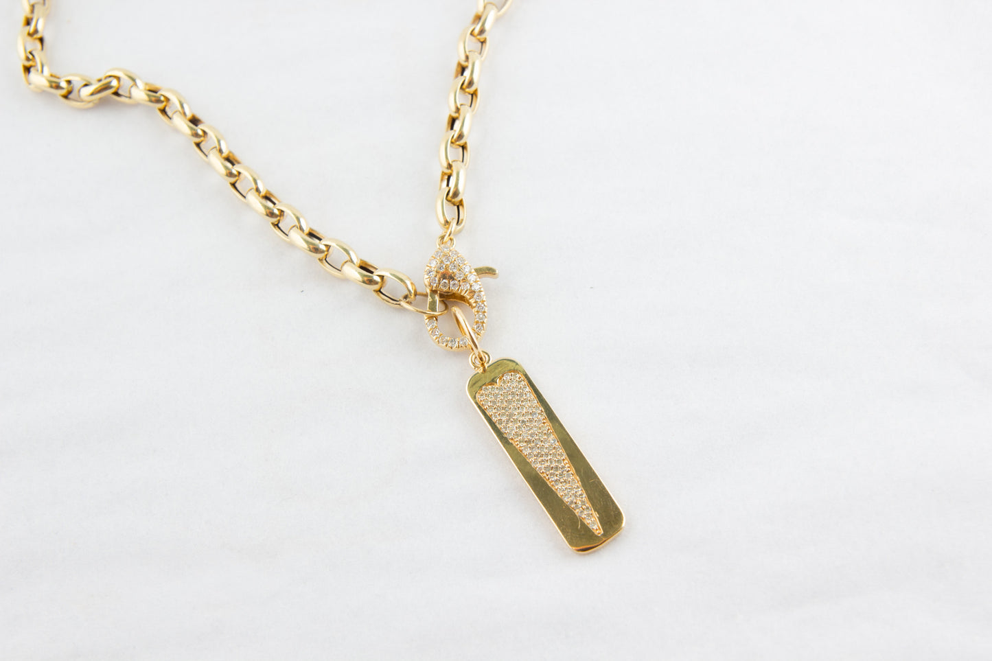Gold necklace with a rectangular pendant on a light gray background
