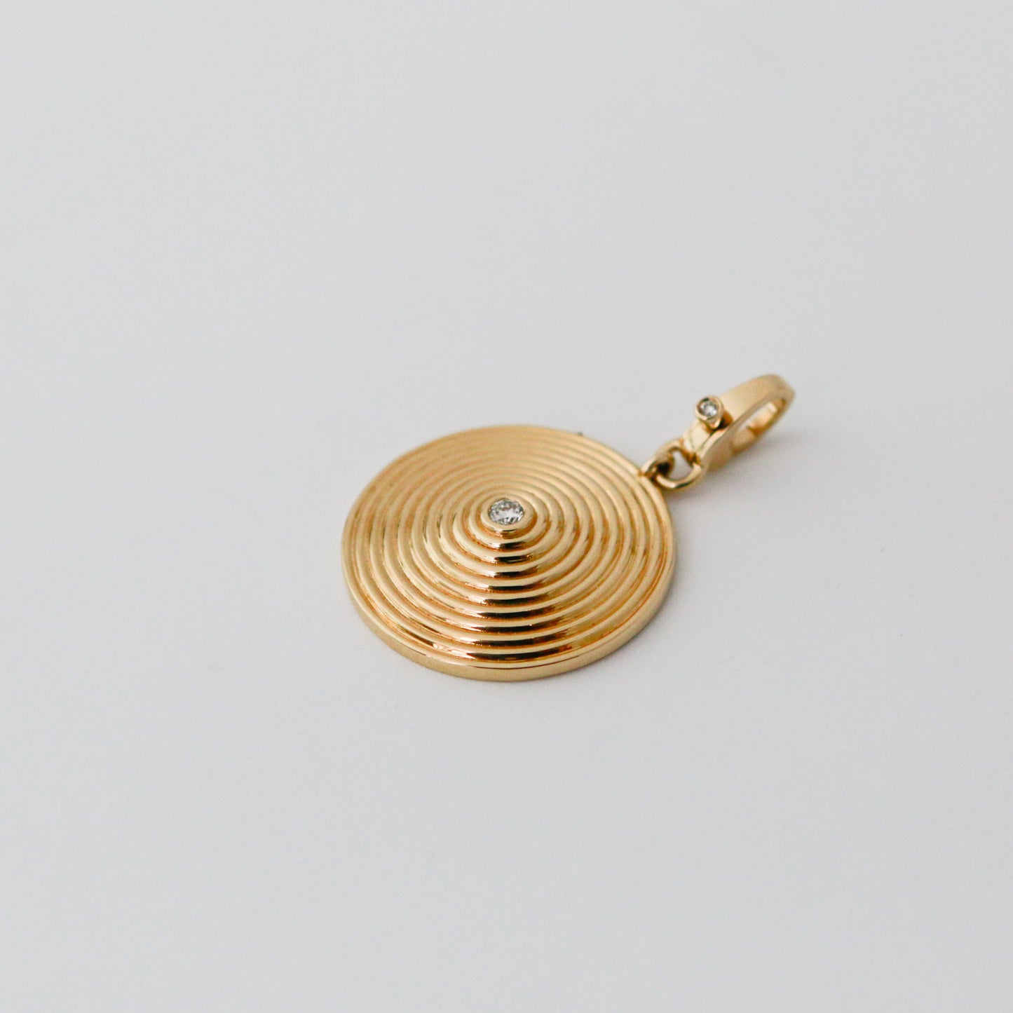 Gold pendant with a diamond on a light gray background