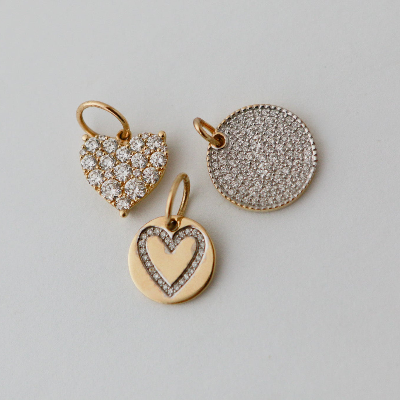 Three heart-shaped pendants on a light gray background