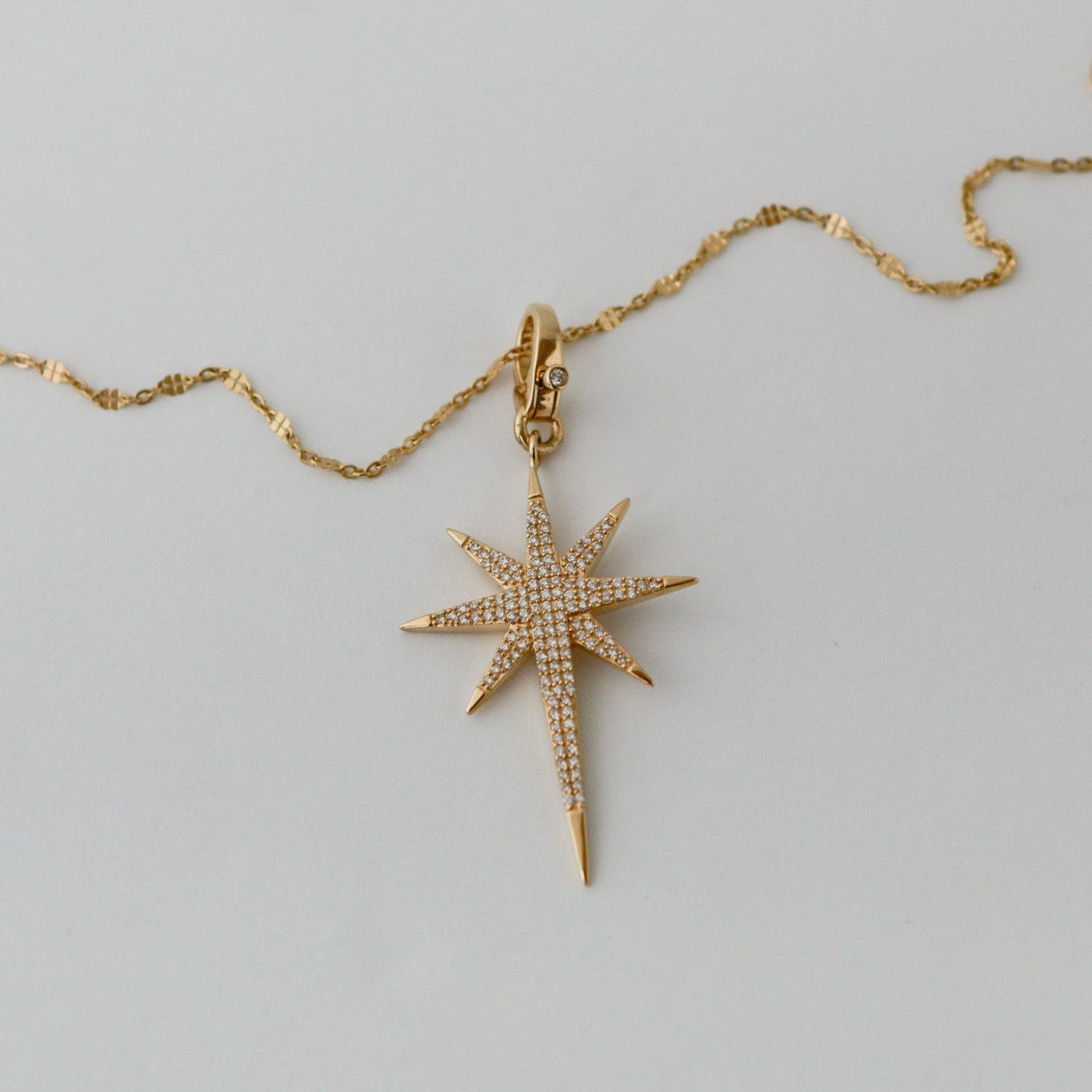 Gold necklace with a star-shaped pendant on a light gray background
