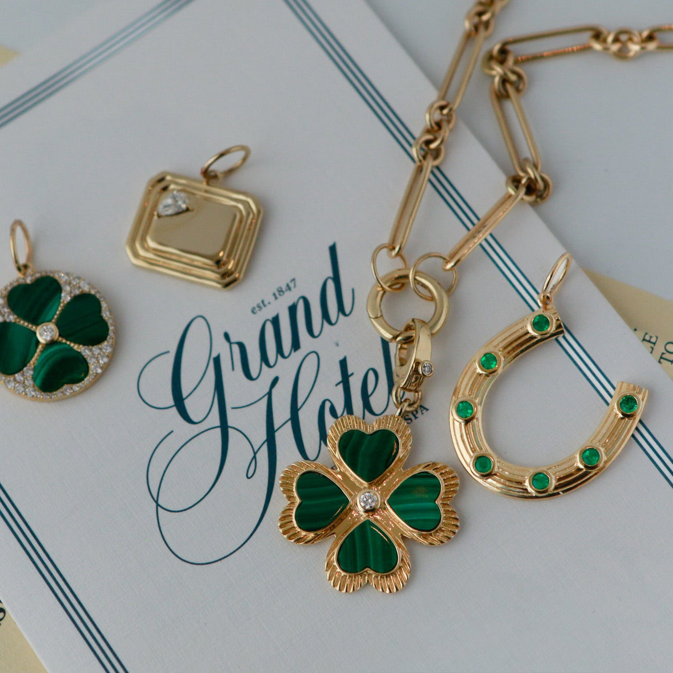 Gold and green jewelry on a 'Grand Hotel' card