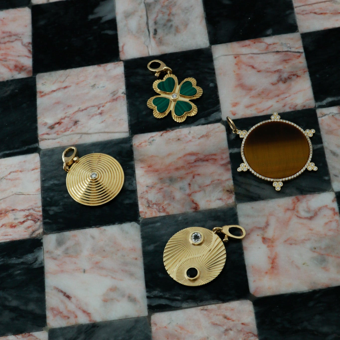 Gold jewelry pendants on a checkered marble surface