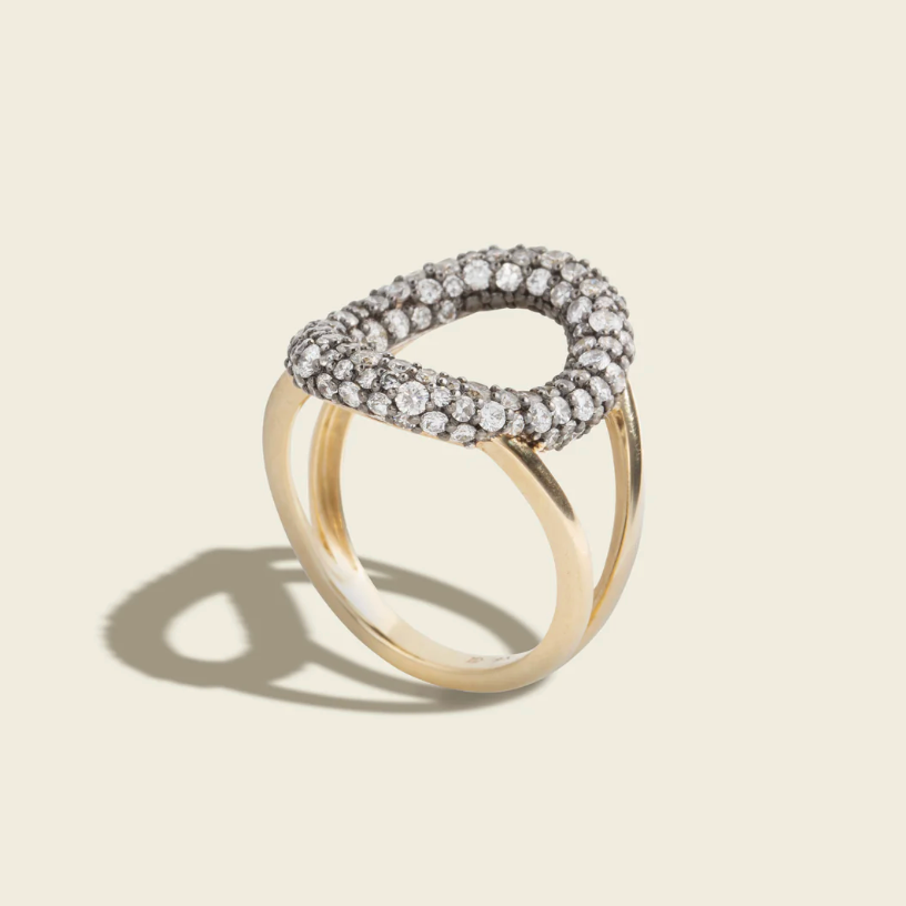 Gold ring with diamond accents on a beige background