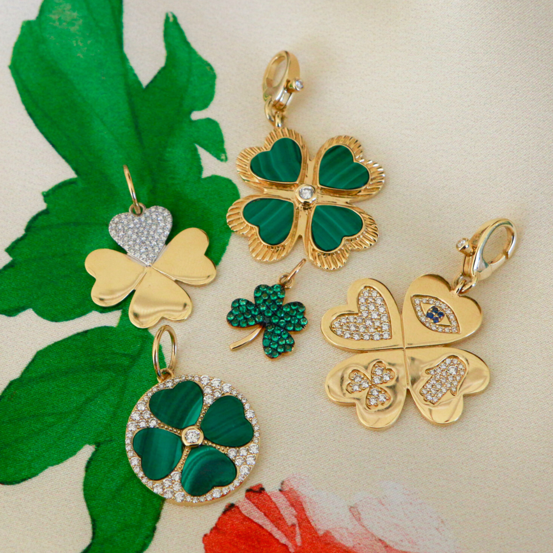 Gold and green four-leaf clover pendants on a floral background