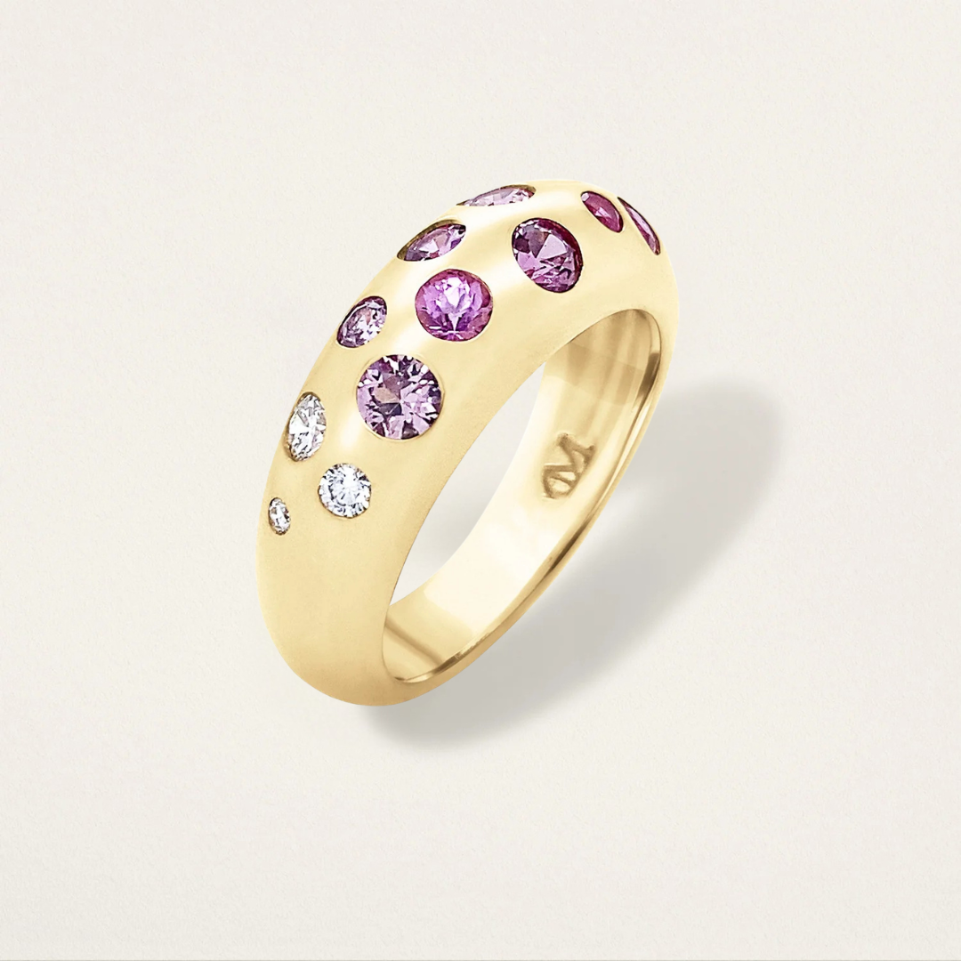 Gold ring with pink and white gemstones on a light gray background