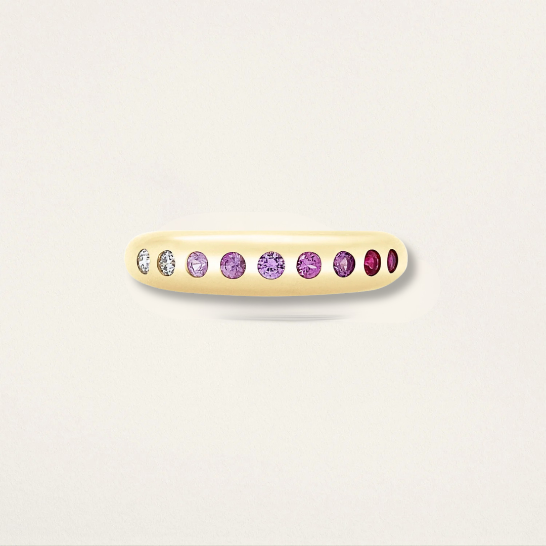Gold ring with purple gemstones on a light gray background