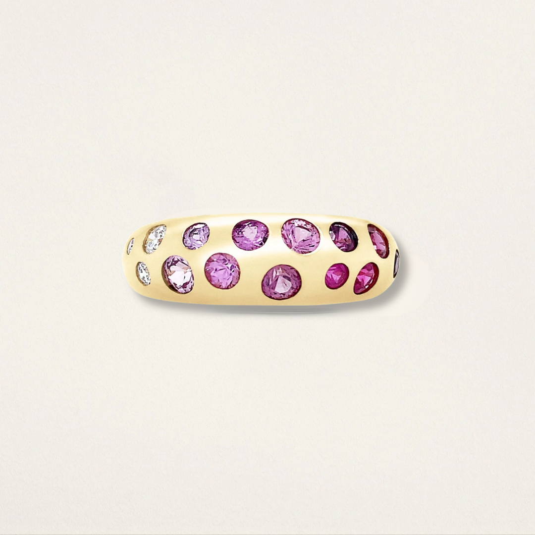 Gold ring with pink gemstones on a light beige background