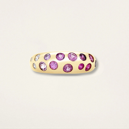 Gold ring with pink gemstones on a light beige background