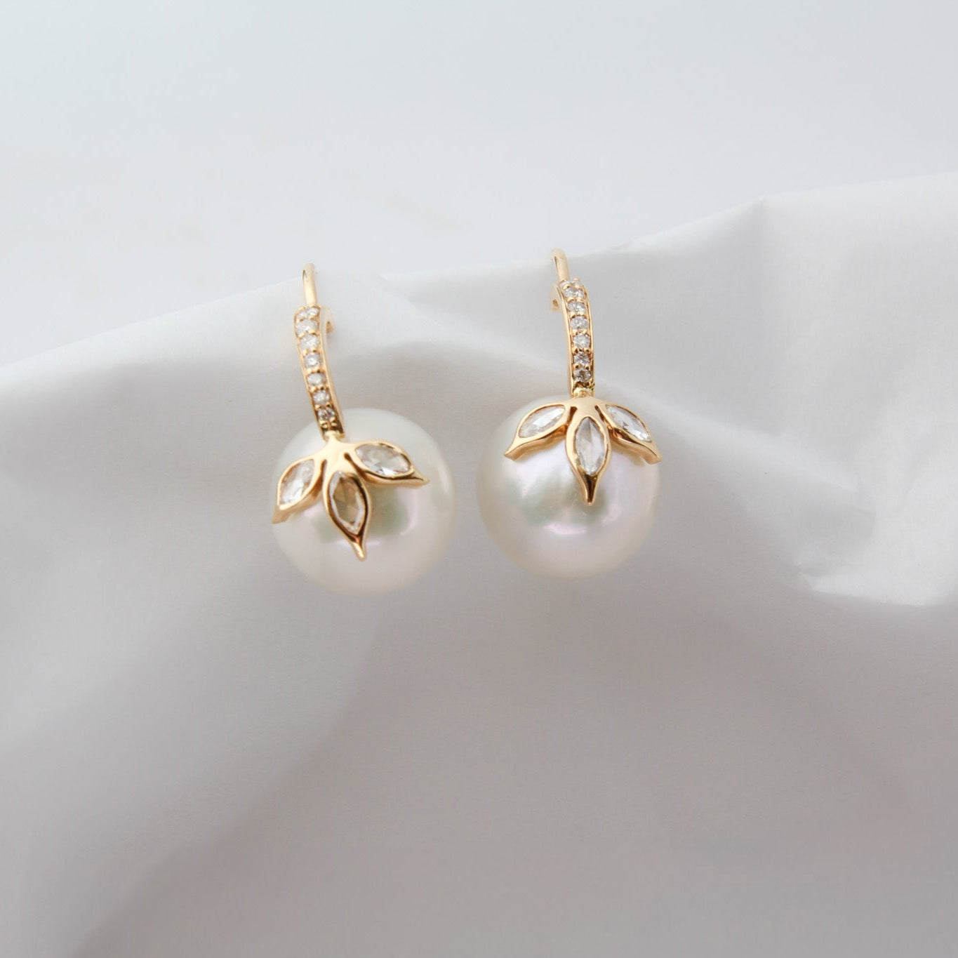Pair of pearl earrings with gold accents on a soft white background
