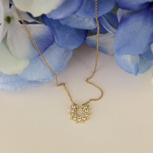 Gold necklace on a white surface with blue flowers in the background