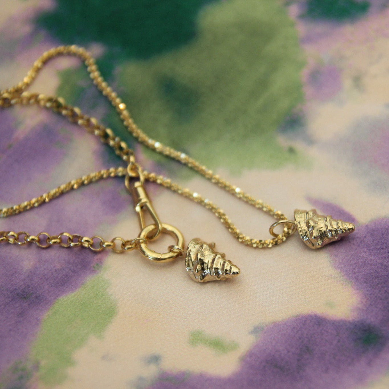 Gold necklace with shell charms on a floral background