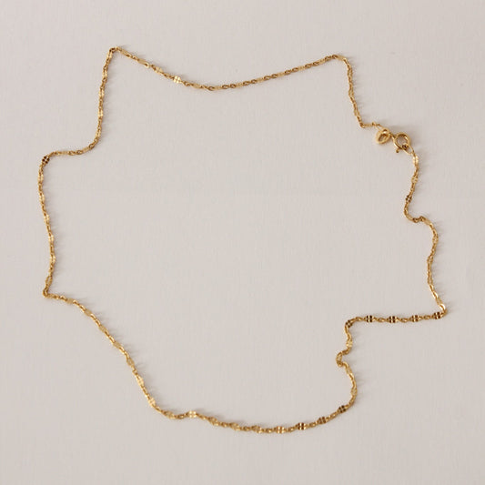 Gold chain necklace on a light gray background
