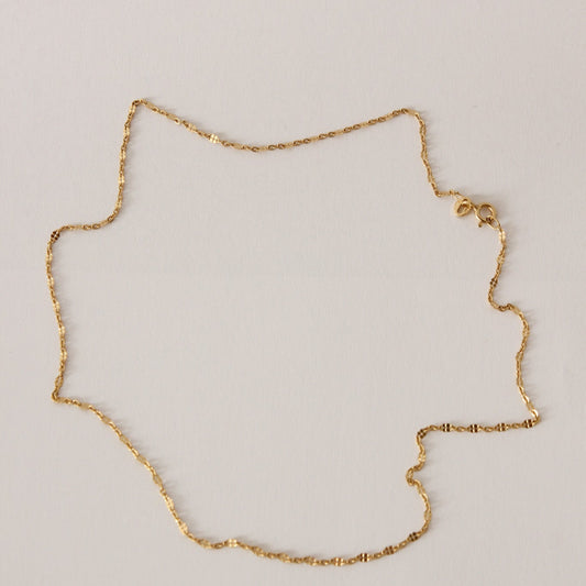 Gold chain necklace on a light gray background