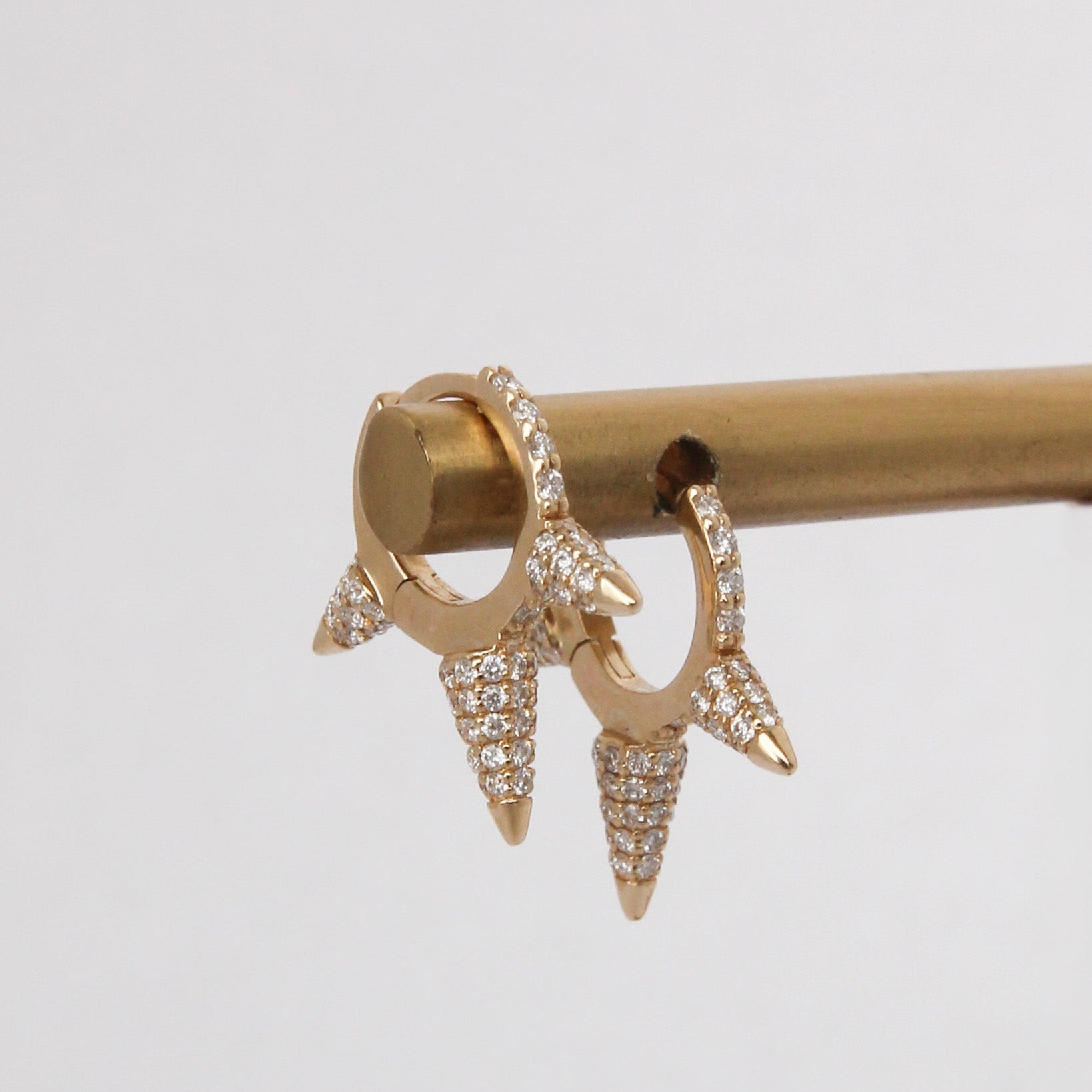 Gold spike earrings on a stick against a light gray background
