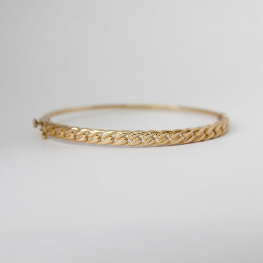 Gold bracelet on a light gray background