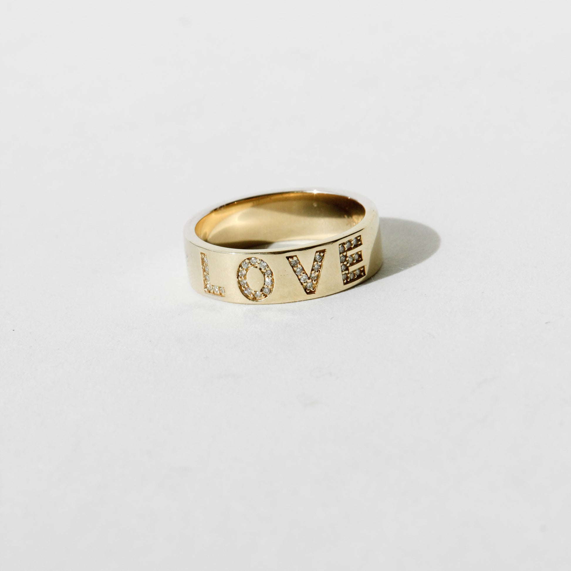 Gold ring with 'LOVE' engraving on a light gray background