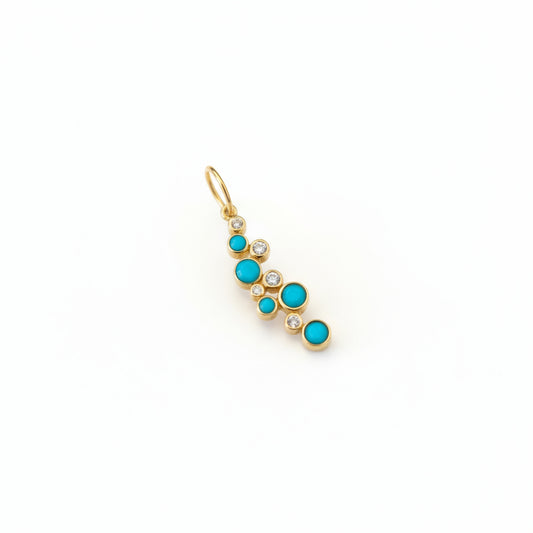 Gold charm with turquoise stones on a marble background