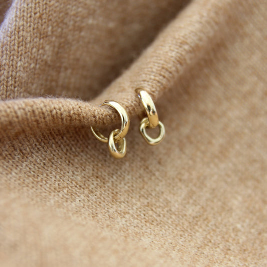 Gold hoop earrings on a beige fabric background