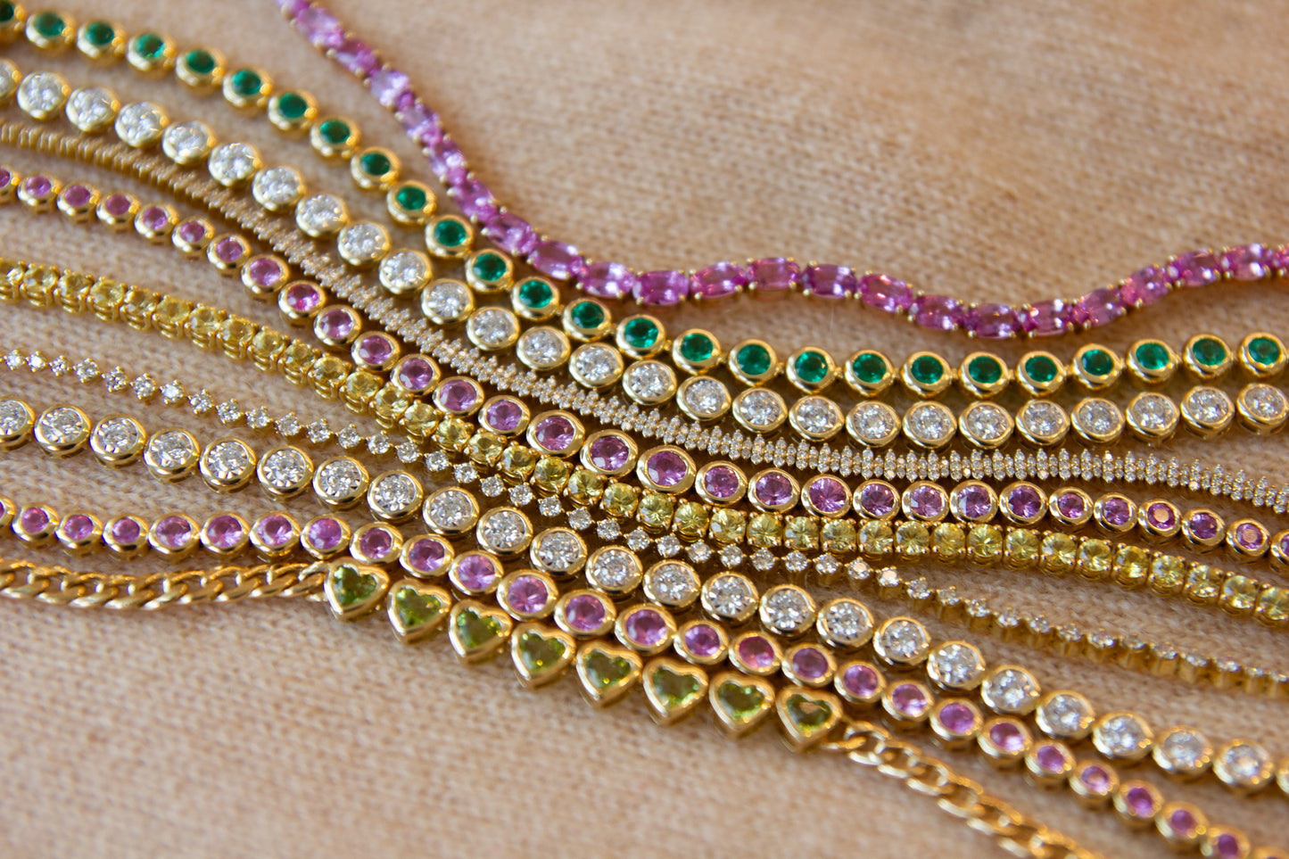 Multiple gold necklaces with gemstones on a wooden surface
