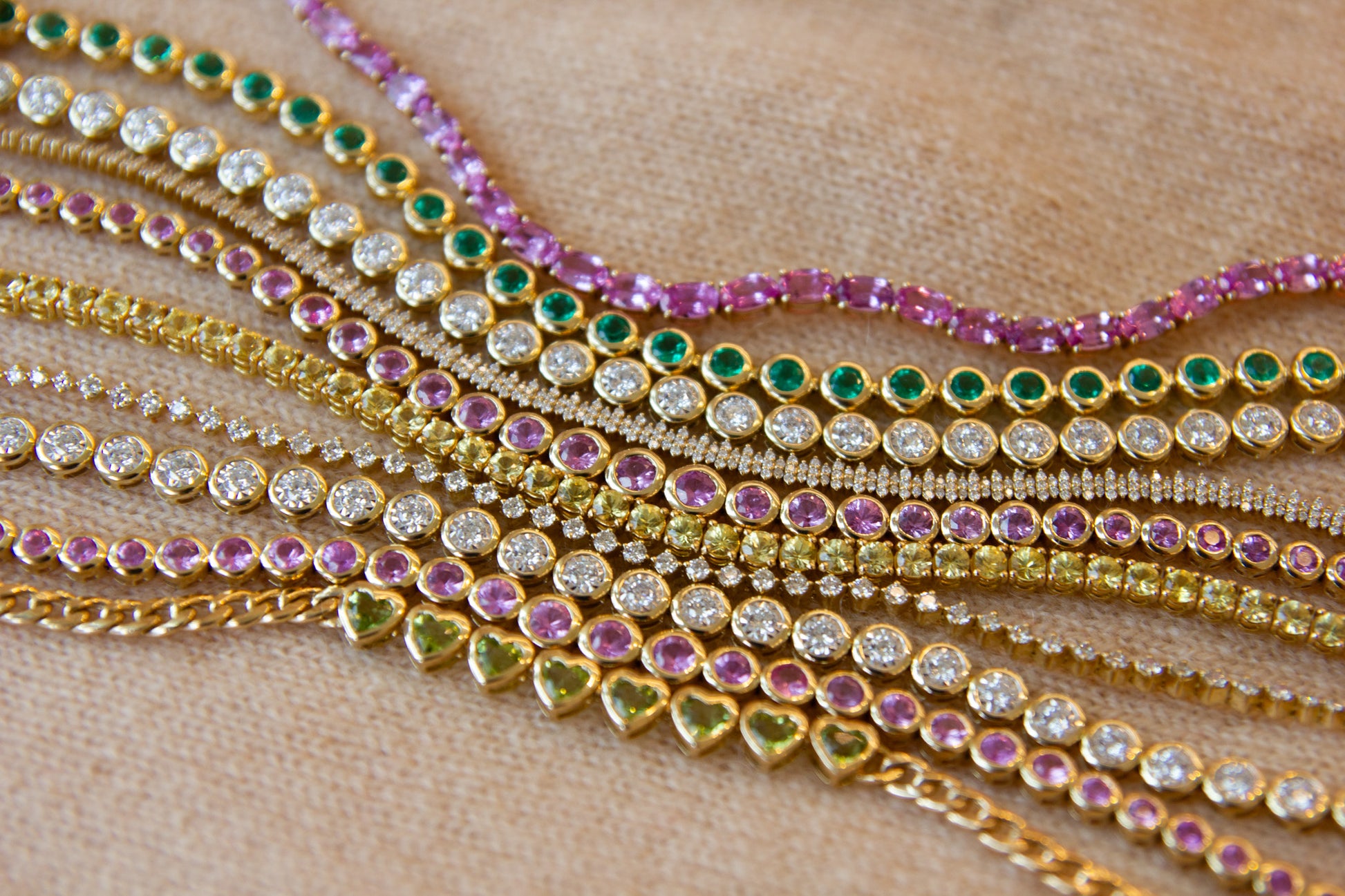 Multiple gold necklaces with gemstones on a wooden surface