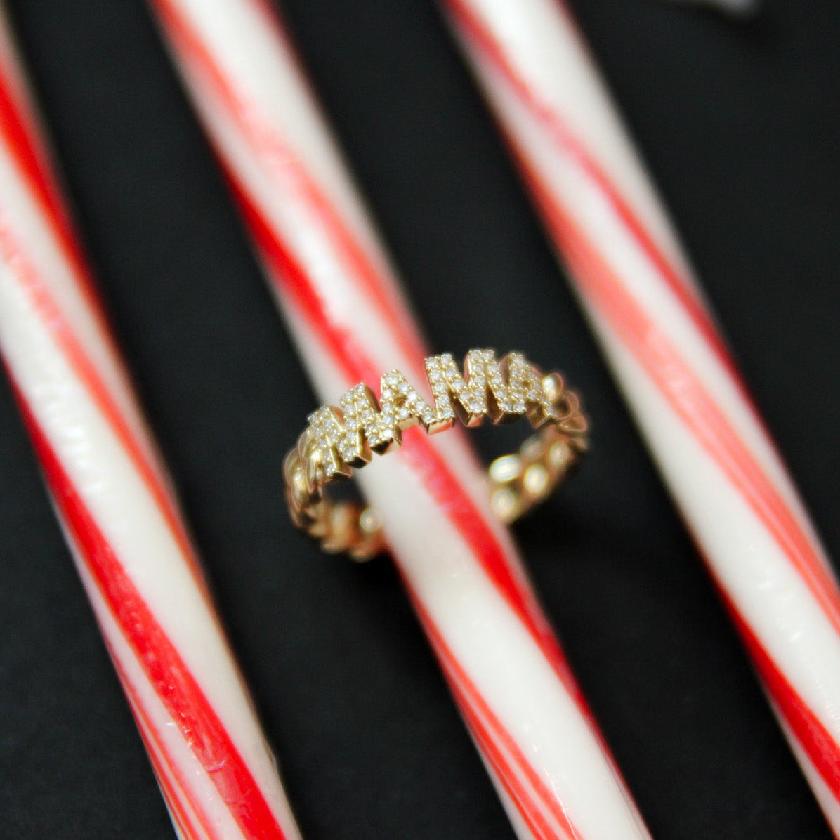Gold ring on a red and white striped candy cane against a black background
