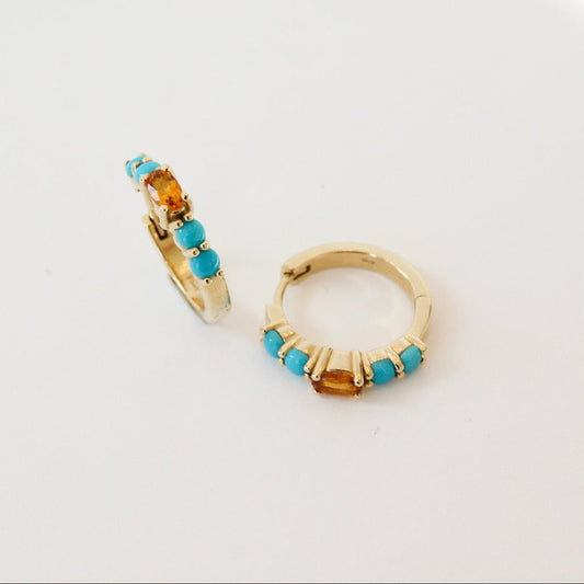 Gold hoop earrings with turquoise and orange beads on a light gray background