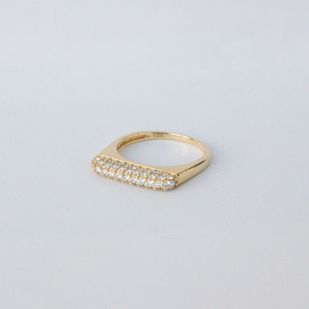 Gold ring with small diamonds on a light gray background