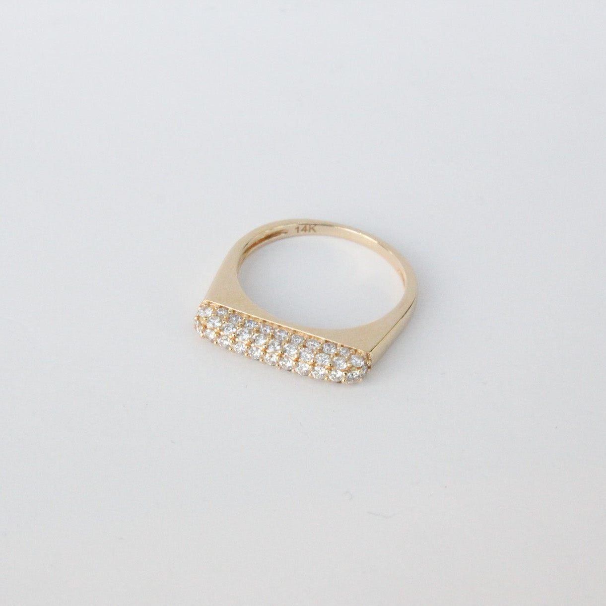 Gold ring with diamonds on a light gray background