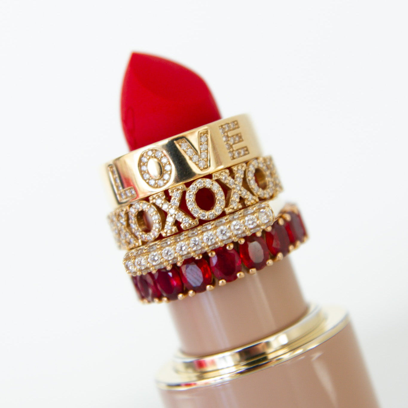 Red lipstick with decorative band featuring 'LOVE' and 'XOXO' on a white background