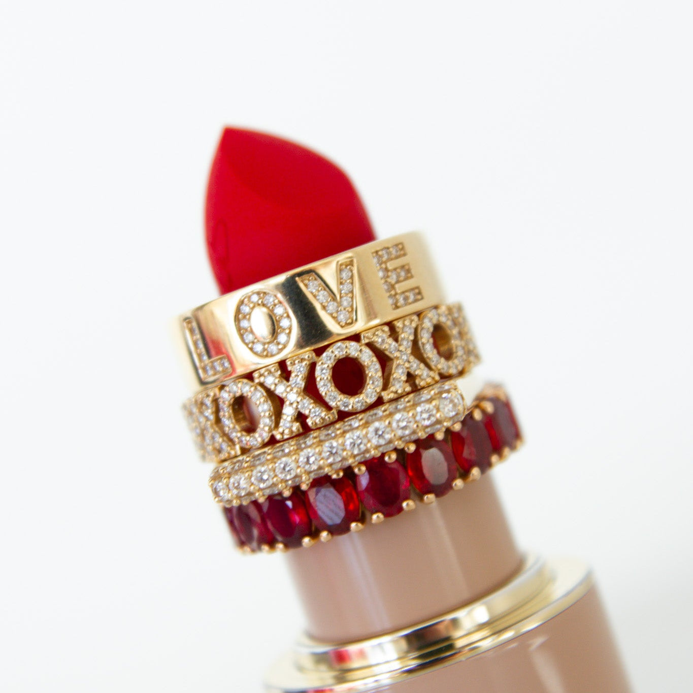 Red lipstick with decorative band featuring 'LOVE' and 'XOXO' on a white background