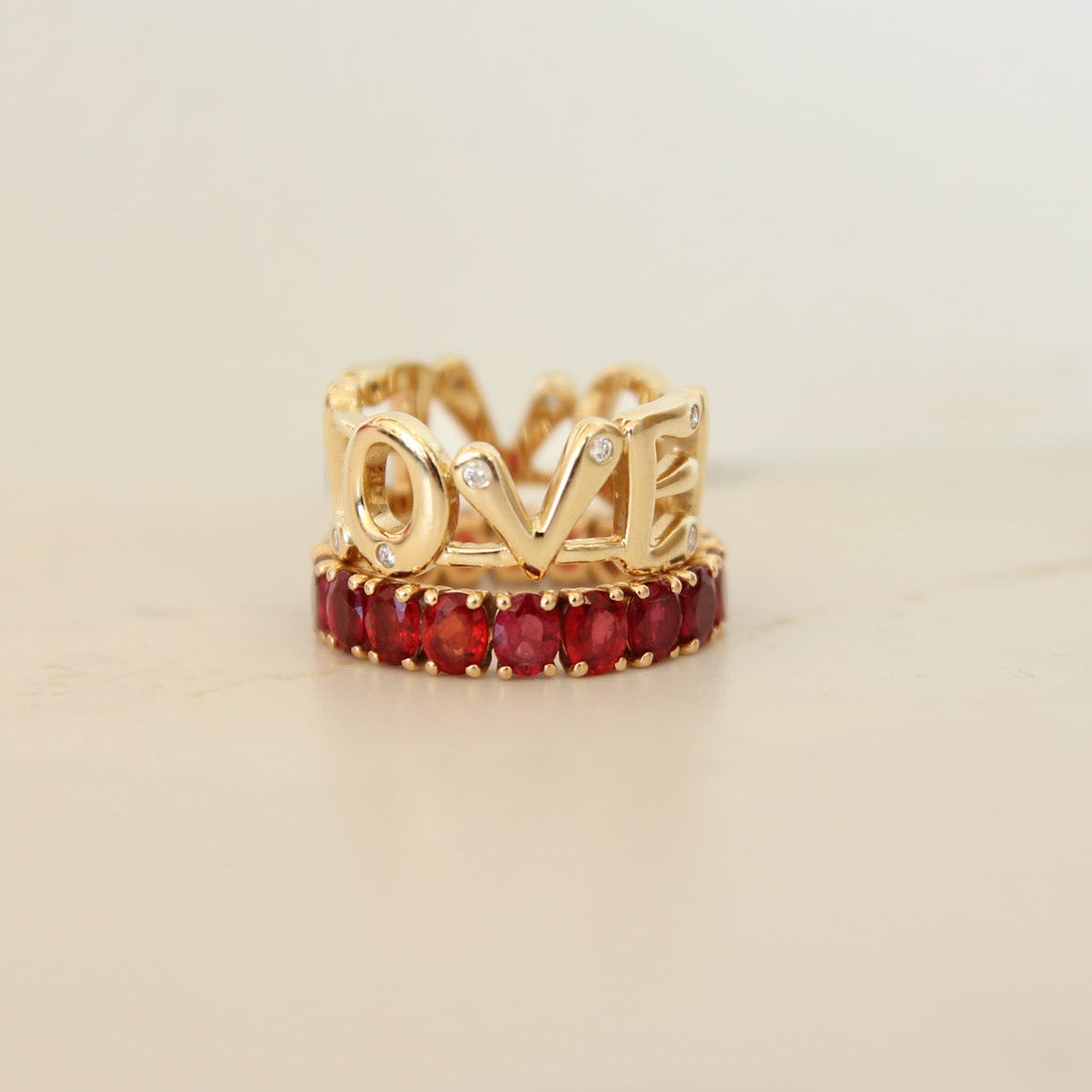 Gold ring with red gemstones on a light beige background