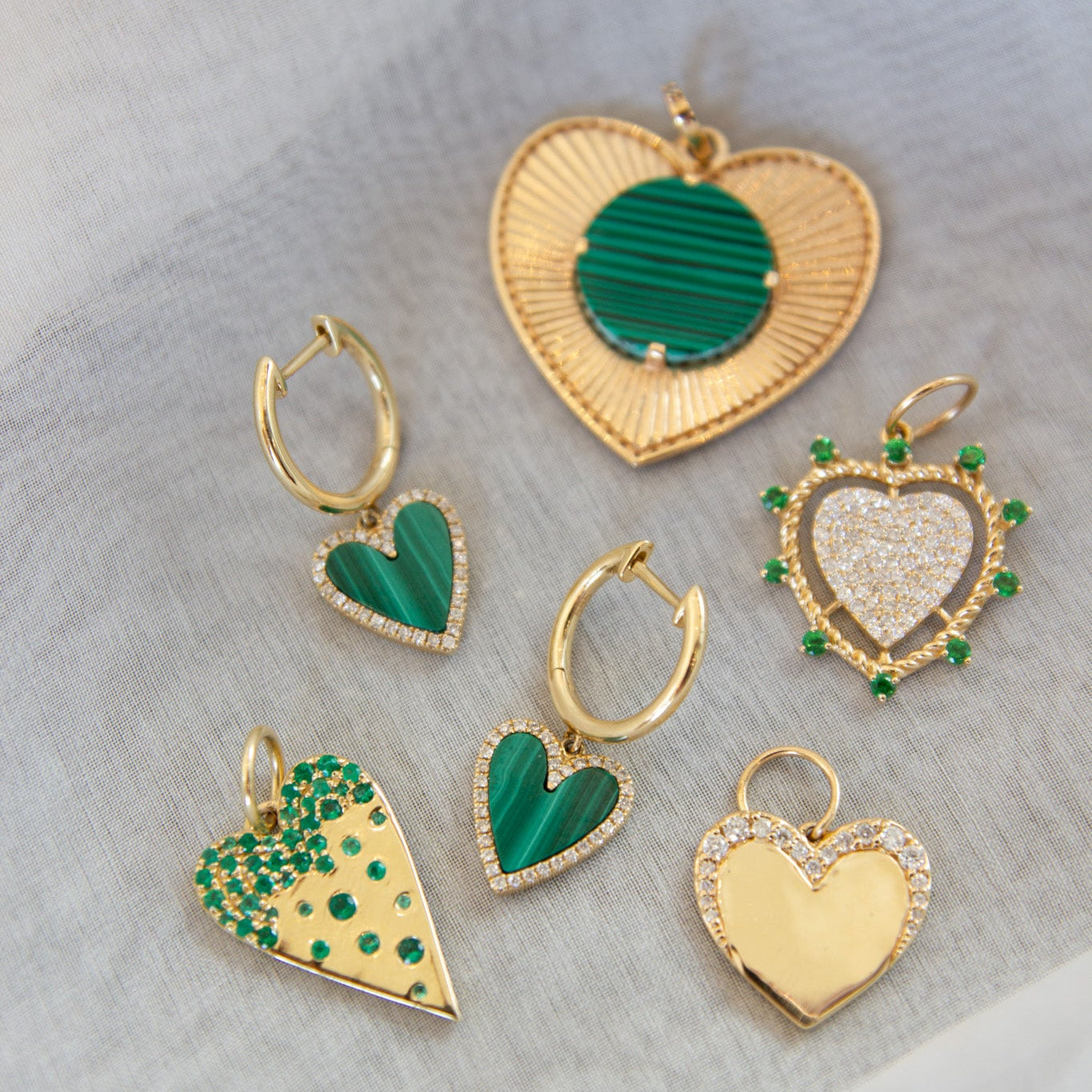 Set of heart-shaped earrings with gold and green accents on a light gray background