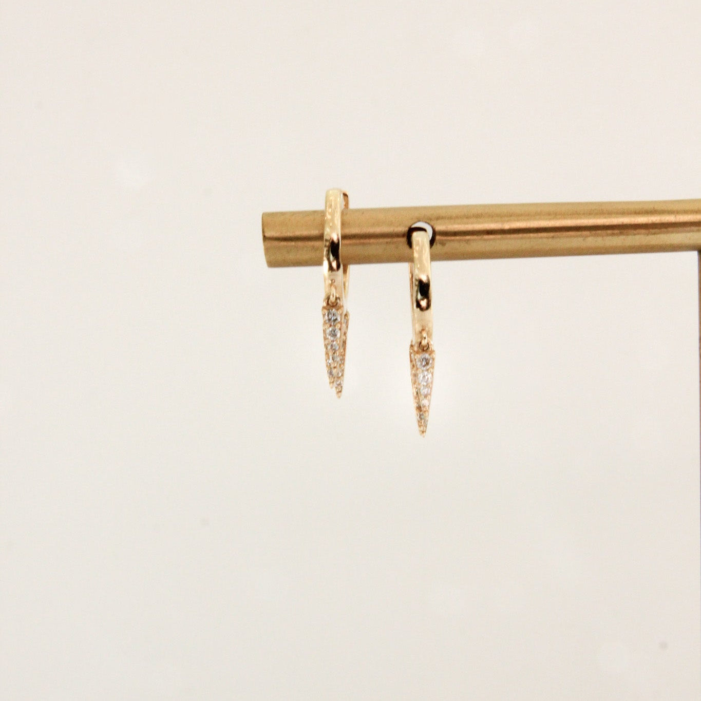 Gold earrings on a beige background